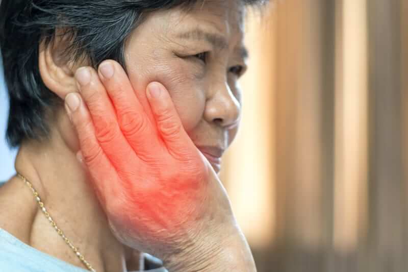 Woman with TMJ pain massaging her jaw joint