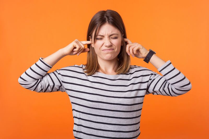 Woman trying to avoid the sound of the dental drill
